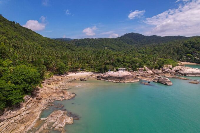 Aerial drone photograph of Koh Phangan showing tropical beaches, lush jungle hills, turquoise waters and island landscapes